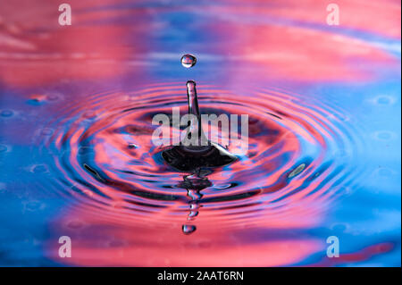 Single water drop at top of splash. Vibrant red and blue colors, high speed water drop photography Stock Photo
