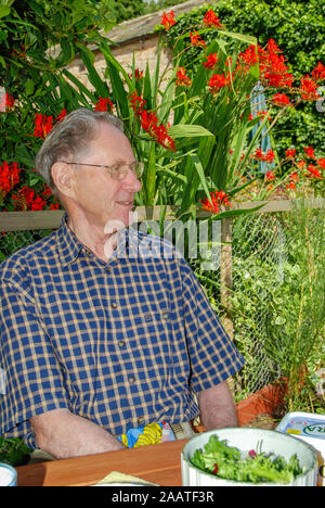 Elderly man enjoys sitting in a garden Stock Photo