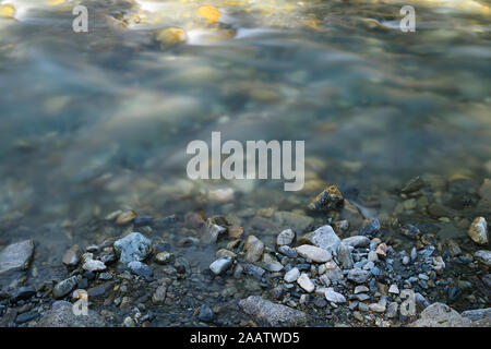 Alpine mountain river with beautiful natural rocks and pebbles. Long exposure photography, capturing motion.