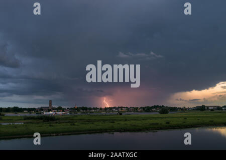 Lightning strikes down to earth from an evening thunderstorm over the dutch river landscape Stock Photo