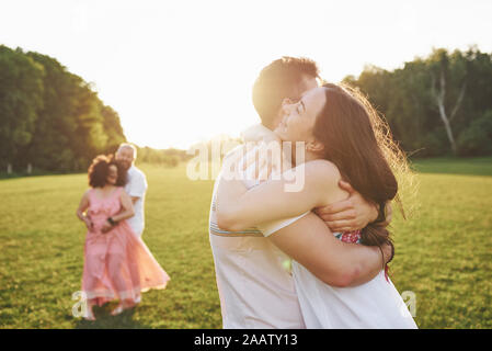 Two families of different generations embrace. Young husband and wife as well as their old parents who still love each other Stock Photo