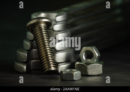 Bolt nuts and wrench on cement floor in darkness. Closeup and copy space for text. Concept of mechanical engineering jobs. Stock Photo