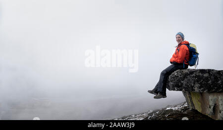 Young woman sitting on rock spur near Dinboche, Solo Khumbu, Nepal Stock Photo