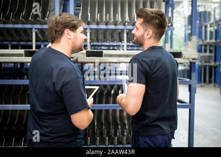 Two workers with clipboard and tablet in factory warehouse Stock Photo