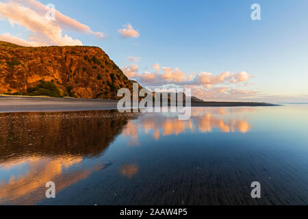 Scenic view of sea by cliff against blue sky at sunset, Oceania, New Zealand Stock Photo