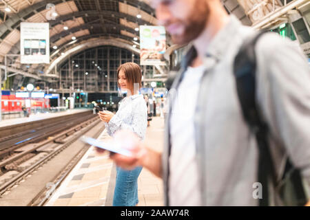 People waiting for the train at the station and using smartphones, Berlin, Germany Stock Photo