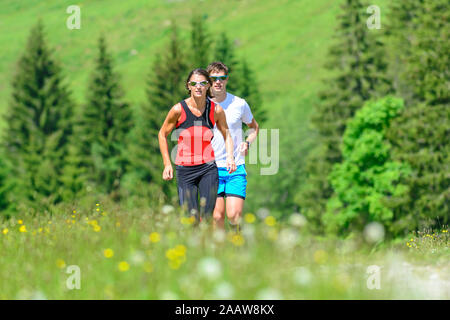 Young people doing a running session in green alpine nature Stock Photo