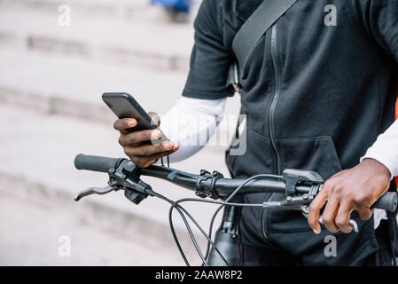 Close-upof man with bicycle using smartphone Stock Photo