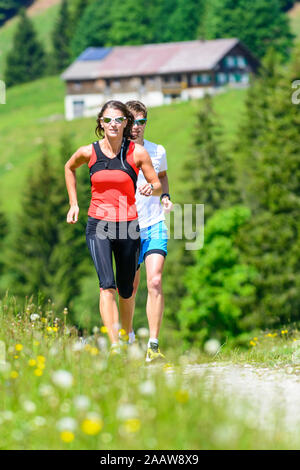 Young people doing a running session in green alpine nature Stock Photo