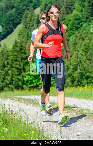 Young people doing a running session in green alpine nature Stock Photo