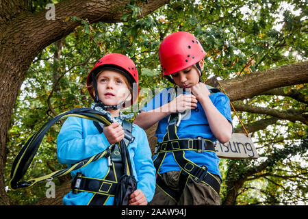 Boy and girl on a high rope course in forest Stock Photo