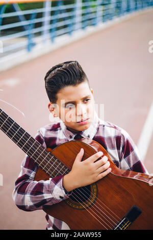 Gypsy boy with guitar on a bridge Stock Photo