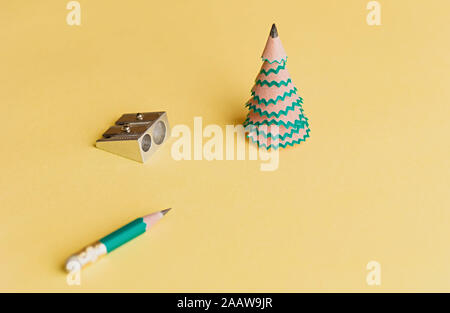 Creative christmas tree. Pencil for shavings, pencil and sharpener on a yellow background. Christmas concept in office. Selective focus. Close up. Stock Photo