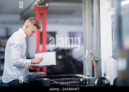 Young man checking printer in a printing company Stock Photo