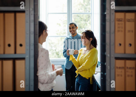 Coleagues chatting and drinking coffee in office kitchenet Stock Photo
