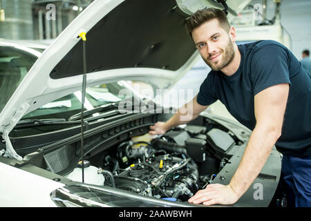 Portrait of confident man working on car in modern factory Stock Photo