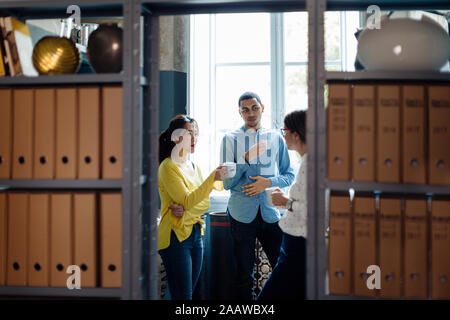 Coleagues chatting and drinking coffee in office kitchenet Stock Photo