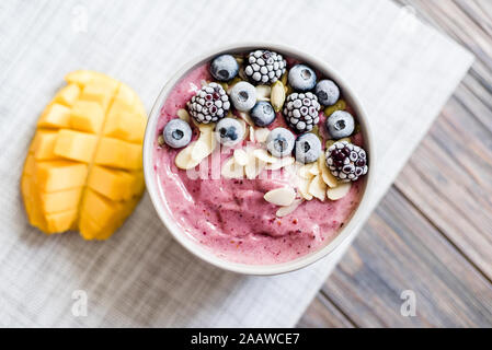 Healthy breakfast berry smoothie bowl topped with Blueberries blackberries, pumpkin seeds and almond flakes with copyspace. delicious mango smoothie b Stock Photo