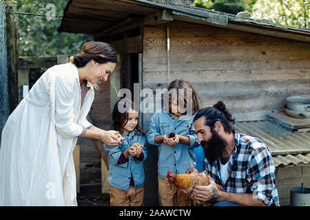 Family with two kids holding chicken and chicks on an organic farm Stock Photo