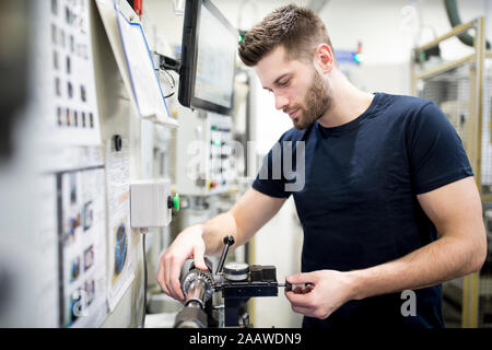 Man working in a modern factory operating a machine Stock Photo
