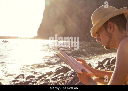 Young man reading a book at the beach Stock Photo