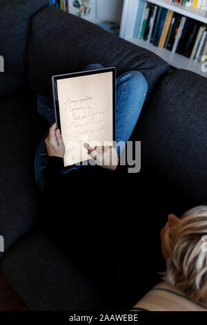 Mature woman relaxing on couch at home using graphics tablet Stock Photo