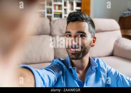 Portrait of smiling young man taking selfie at home Stock Photo