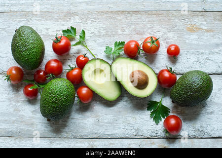 Directly above shot of avocados with tomatoes and parsley on wooden table Stock Photo