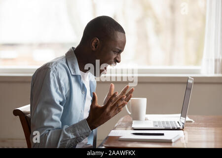Furious biracial man scream having computer problems Stock Photo