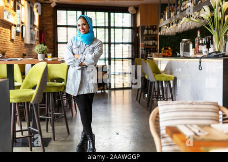 Young woman wearing turquoise hijab in a cafe Stock Photo