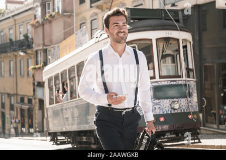 Smiling young businessman in the old town on the go, Lisbon, Portugal Stock Photo
