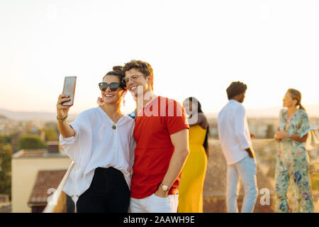 Young woman and man taking a selfie during a party in the evening Stock Photo