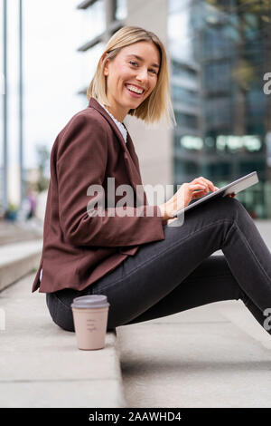 Portrait of happy young businesswoman using tablet in the city Stock Photo