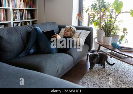 Mature woman relaxing on couch at home reading a book Stock Photo