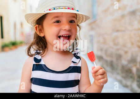 Portrait of happy little girl with red lollipop in summer Stock Photo
