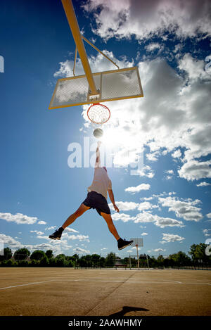 Man playing basketball on yellow court, dunking Stock Photo