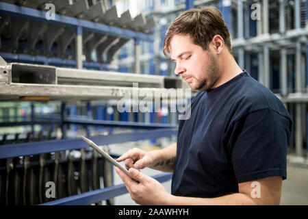 Worker using tablet in factory warehouse Stock Photo
