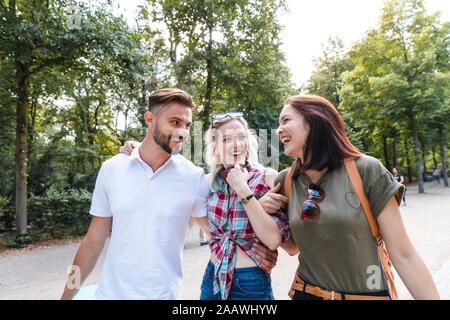 Group of three friends strolling together in a park having fun Stock Photo