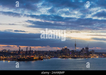 Modern buildings by sea against cloudy sky at dusk in Auckland, New Zealand