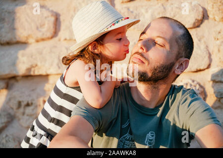 Little girl kissing her father at sunset Stock Photo