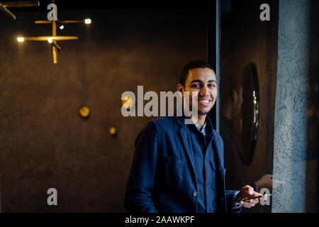 Young man in stylish office, using smartphone Stock Photo
