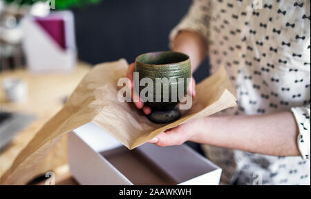 Close-up of woman wrapping an earthenware mug Stock Photo