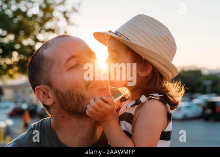 Little girl kissing her father at sunset Stock Photo