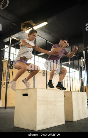 Young couple doing box jump exercise during cross training Stock Photo