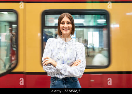 Young woman at train station with blurred train as background Stock Photo
