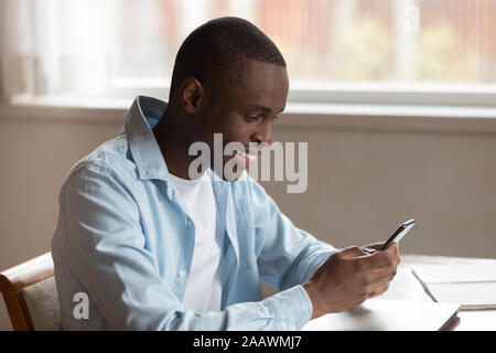 Smiling biracial man using modern smartphone texting Stock Photo