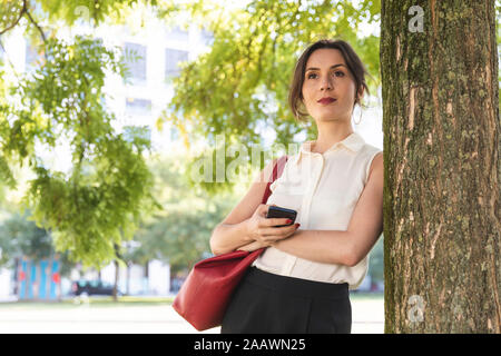 Young businesswoman with cell phone in a park Stock Photo