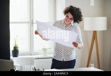 Smiling young woman studying a plan in office Stock Photo