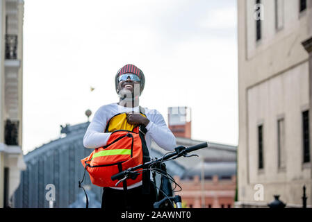 Happy stylish young man with bicycle and messenger bag in the city Stock Photo