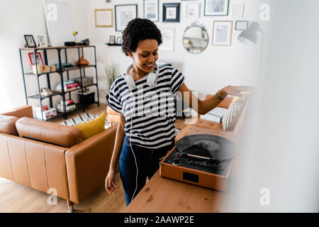 Young woman using record player at home Stock Photo